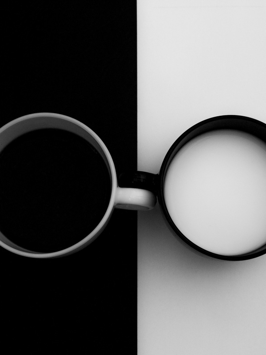 Schwarz-Weiß-Poster mit zwei Tassen, eine mit Kaffee auf schwarzem Hintergrund und eine mit Milch auf weißem Hintergrund.
