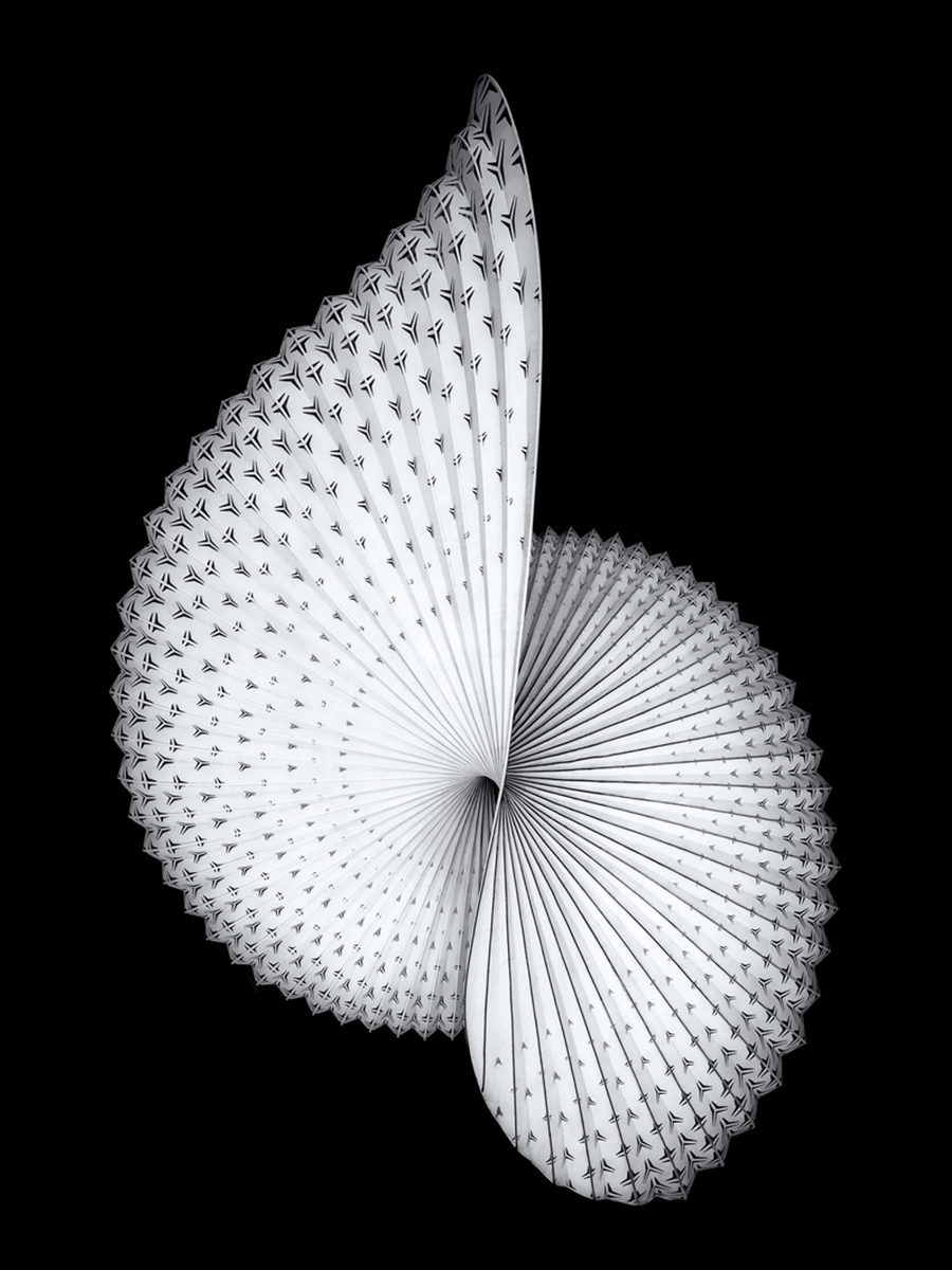 Papierkunstwerk in spiralförmiger, skulpturaler Form vor schwarzem Hintergrund.