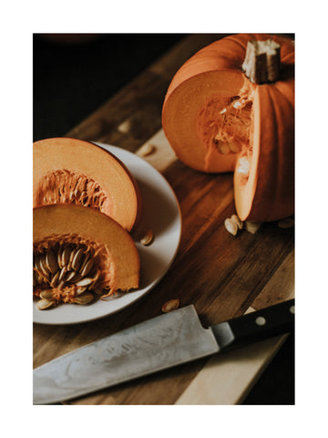 Fotografie von geschnittenem Kürbis auf einem Holzbrett mit einem Messer daneben.