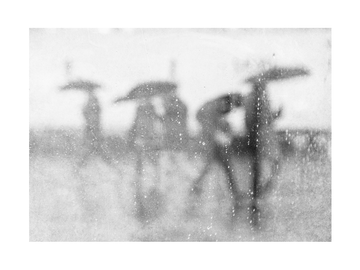 Verschwommene Schwarz-Weiß-Szene von Menschen mit Regenschirmen im Regen.