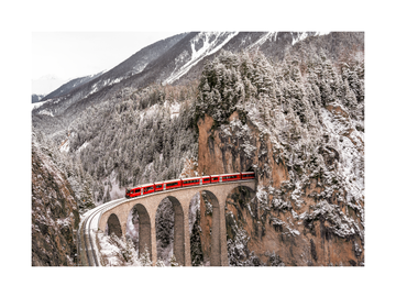 Roter Zug auf einem Viadukt in einer verschneiten Berglandschaft.