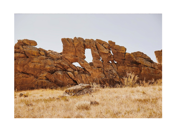 Fotografie von braunen Felsen und Steinen in einer Wüste mit klarem Himmel.