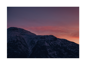Berglandschaft bei Sonnenuntergang mit rosa und orangefarbenem Himmel.