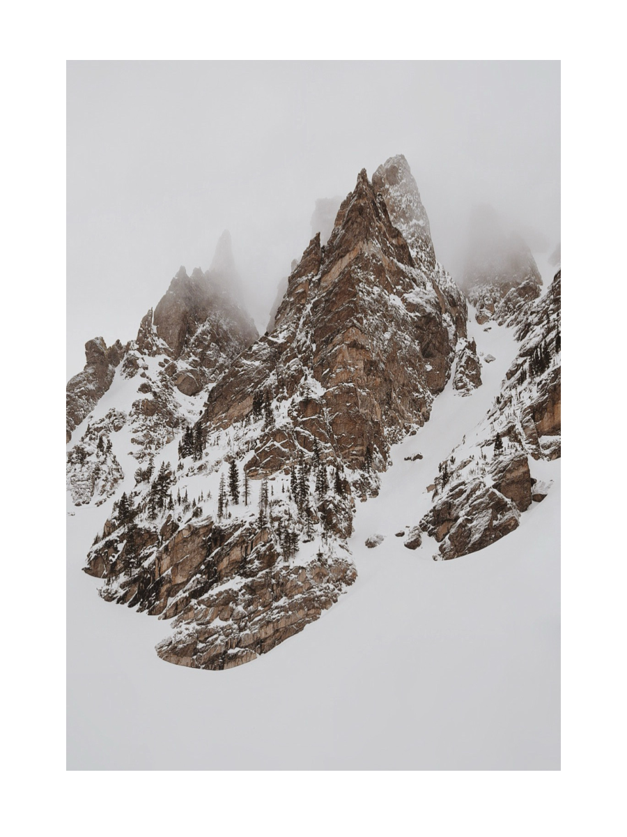 Fotografie von schneebedeckten Berggipfeln mit Wolken im Hintergrund.