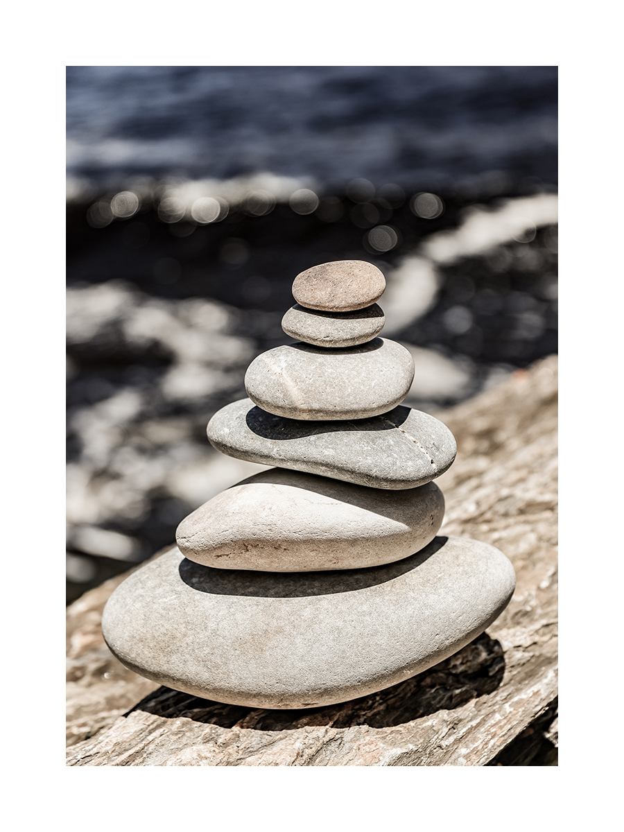 Fotografie von ausgewogenen Steinen vor dem Meer.