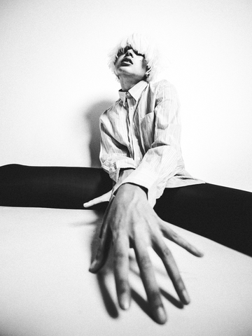 Schwarz-Weiß-Foto einer Person in einer Stretching-Pose mit gestreiftem Hemd.