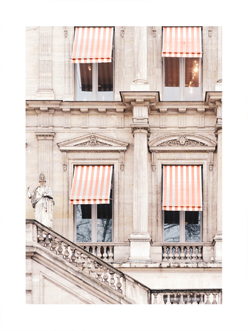 Fotografie einer beigen Hausfassade mit roten und weißen gestreiften Markisen über den Fenstern.