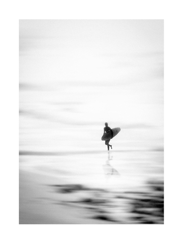 Schwarzweiß-Bild eines Surfers mit Surfbrett am Strand.