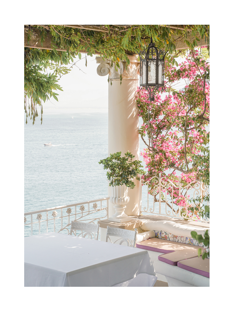 Terrasse mit Meerblick, dekoriert mit Pflanzen und Blumen.