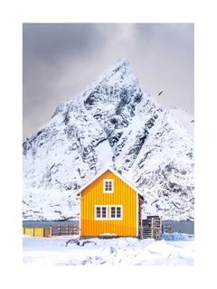 Ein gelbes Haus vor einer schneebedeckten Berglandschaft.