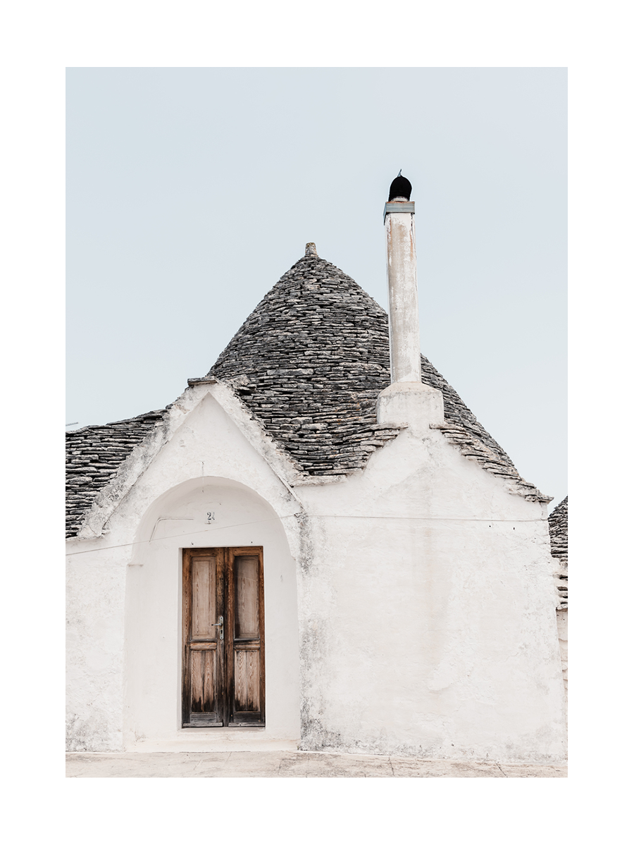 Fotografie eines weißen Trulli-Hauses mit Kegeldach und Holzhaustür.