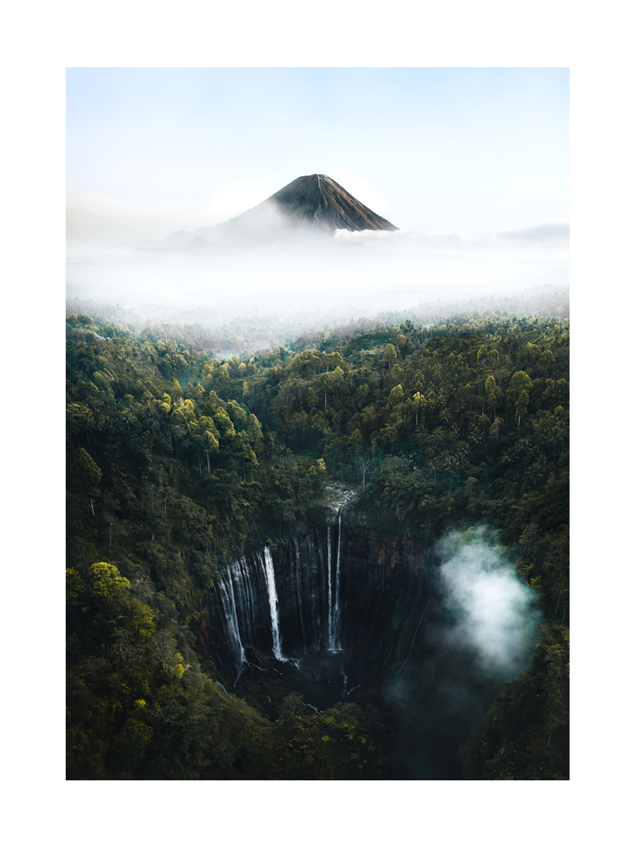 Landschaftsfotografie eines Wasserfalls im Wald mit einem Berg im Hintergrund.