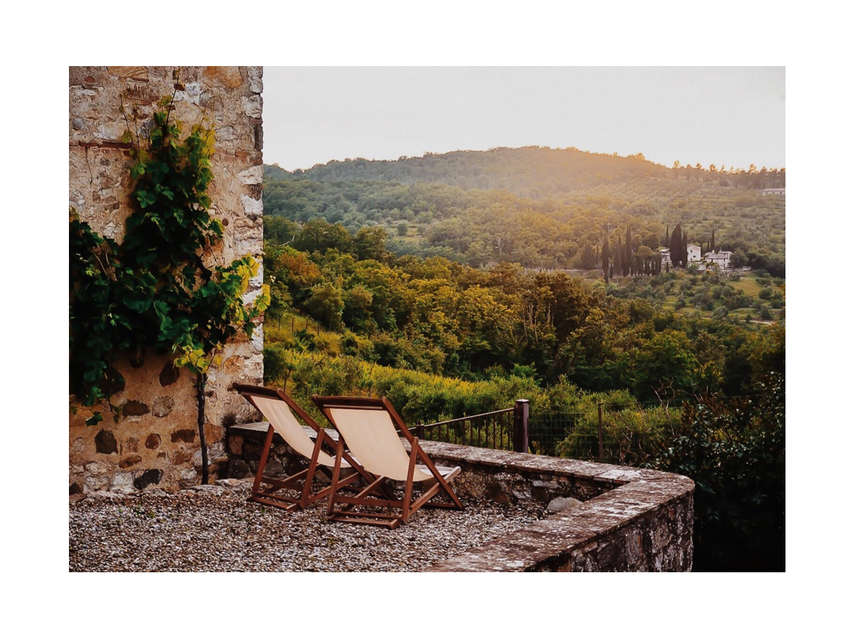 Fotografie von zwei Sonnenstühlen mit Blick auf eine toskanische Landschaft mit grünen Hügeln und Wald.