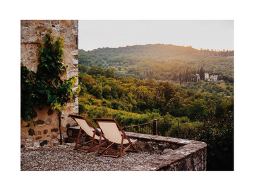 Fotografie von zwei Sonnenstühlen mit Blick auf eine toskanische Landschaft mit grünen Hügeln und Wald.