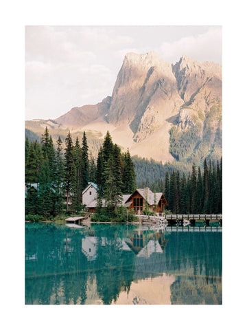 Fotografie von Häusern und Bäumen an einem See mit einem Berg im Hintergrund.