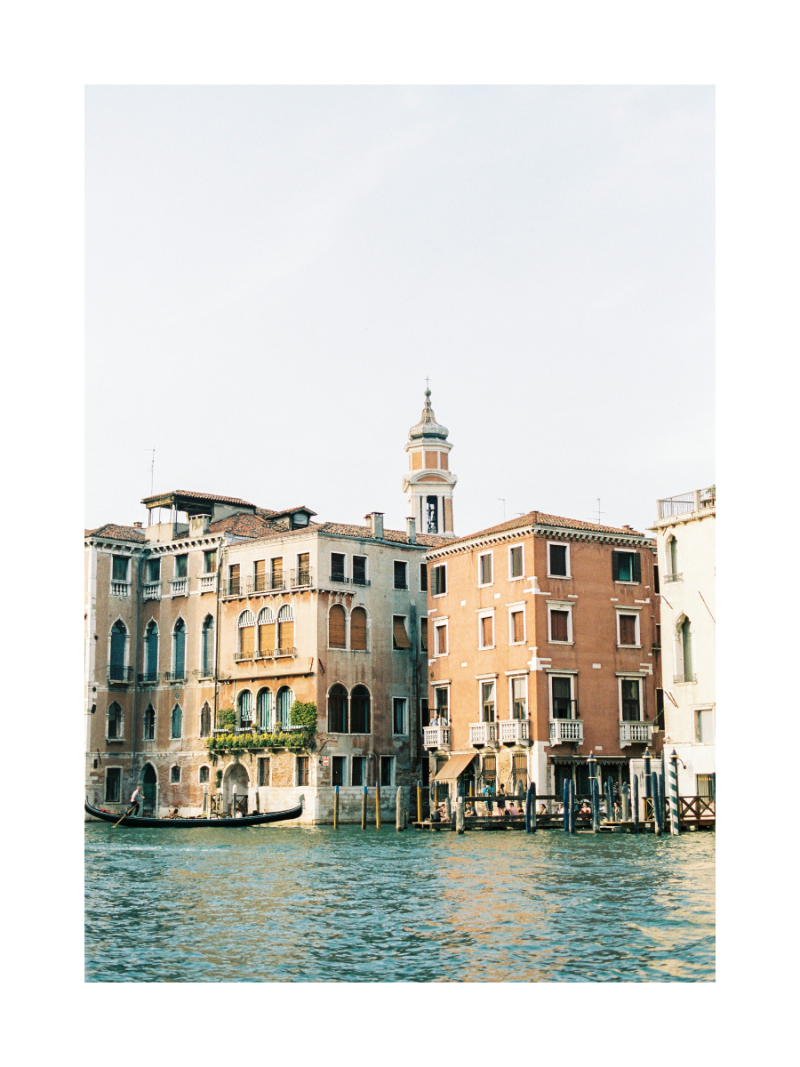 Fotografie von bunten Gebäuden am Wasser in Venedig mit einem Turm im Hintergrund.