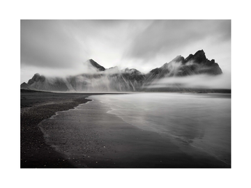 Schwarz-Weiß-Fotografie von Vestrahorn-Bergen mit ruhigem Wasser im Vordergrund.