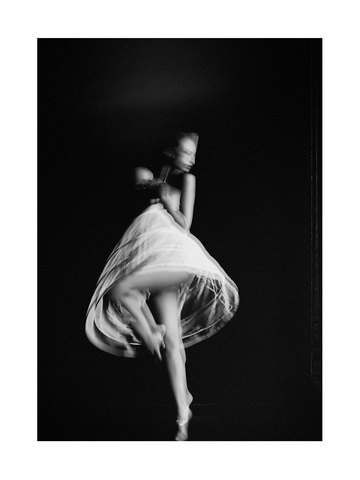 Schwarz-weiß-Fotografie einer Ballerina in einem weißen Kleid, die in der Luft tanzt.