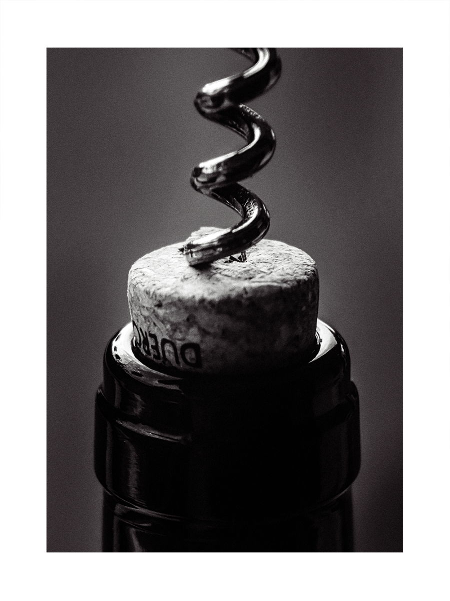 Nahaufnahme eines Korkenziehers, der in einen Weinkorken gedreht wird, in Schwarz-Weiß.