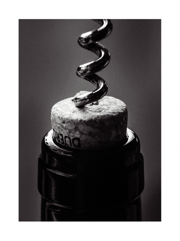 Nahaufnahme eines Korkenziehers, der in einen Weinkorken gedreht wird, in Schwarz-Weiß.