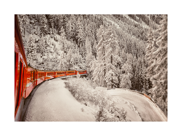 Fotografie eines roten Zuges in einer verschneiten Winterlandschaft.