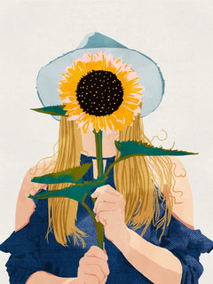 Eine Frau hält eine große Sonnenblume vor ihr Gesicht und trägt einen blauen Hut.