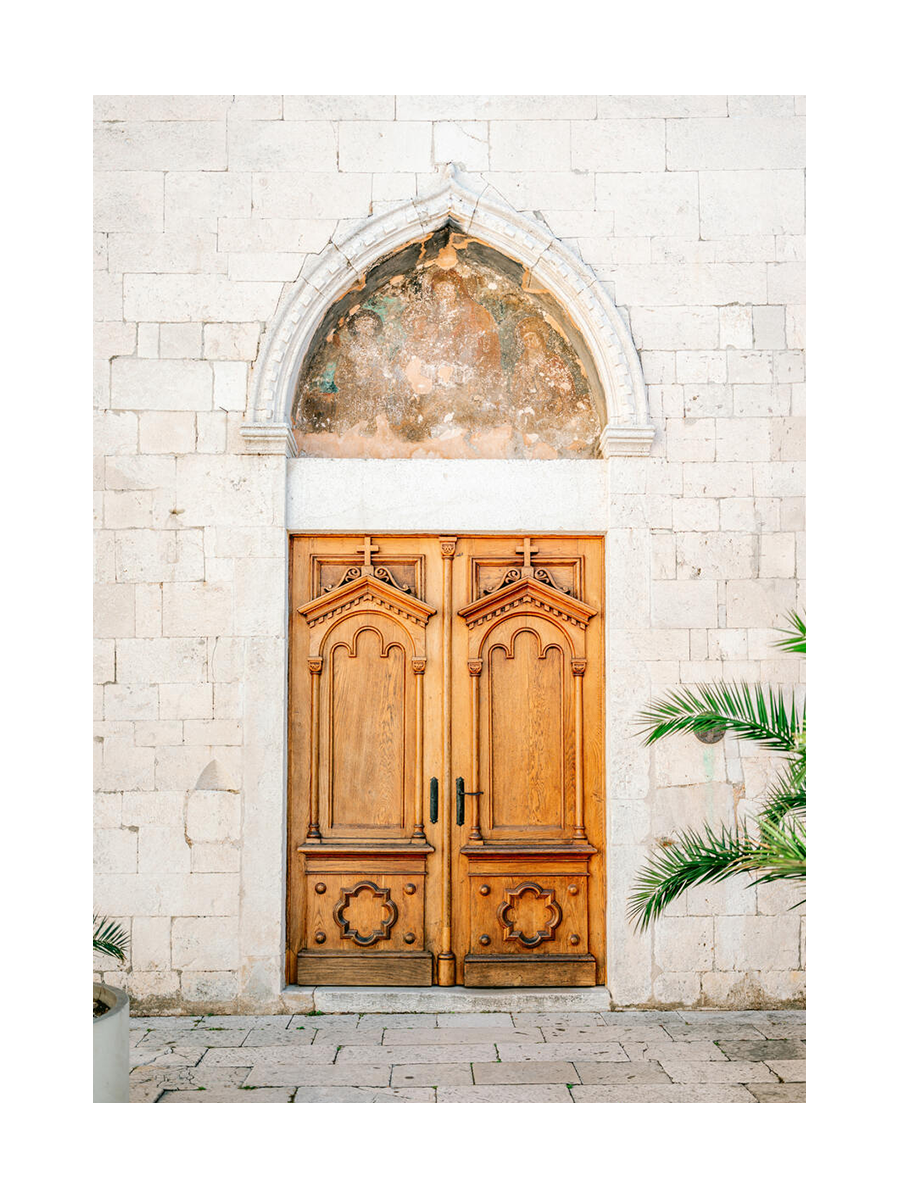 Fotografie einer hölzernen Doppeltür mit Bogen und grünen Pflanzen.