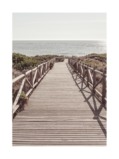 Fotografie eines Holzstegs, der zu einem Strand führt, mit dem Meer im Hintergrund.