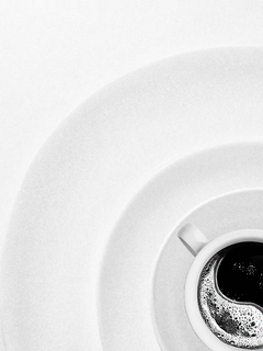 Schwarz-weiß-Fotografie einer Kaffeetasse auf einem Teller, von oben gesehen, mit Yin-Yang-Muster.