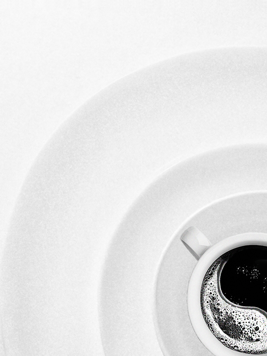 Schwarz-weiß-Fotografie einer Kaffeetasse auf einem Teller, von oben gesehen, mit Yin-Yang-Muster.